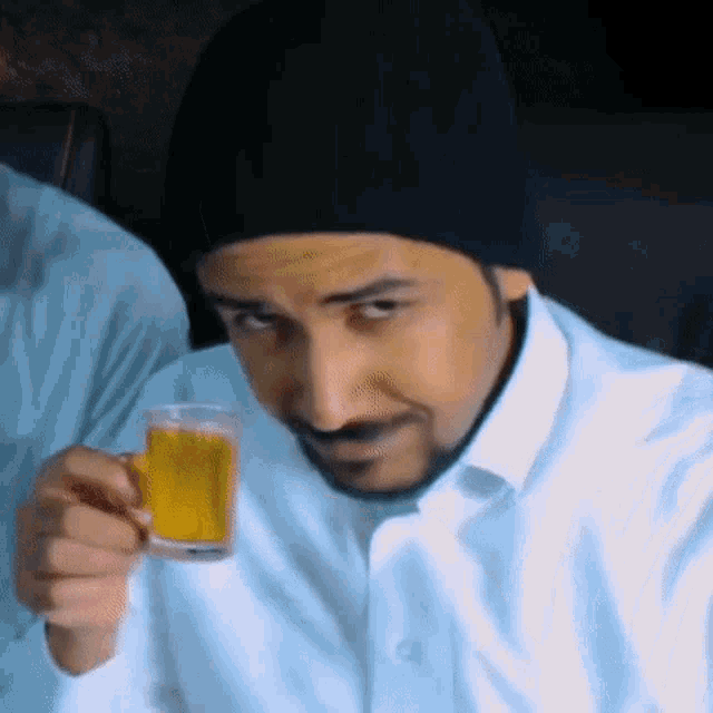 a man wearing a beanie is holding a glass of beer .