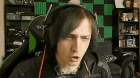 a man wearing headphones is talking into a microphone and making a face .