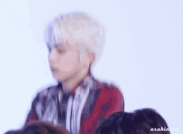 a blurry picture of a man with white hair and a red shirt .