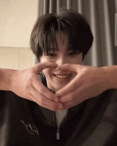 a person making a heart shape with their hands on a person 's face
