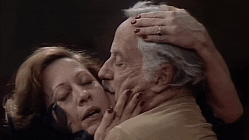 a woman with a ring on her finger kisses an older man on the forehead