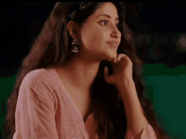 a woman with long hair is wearing a pink dress and earrings