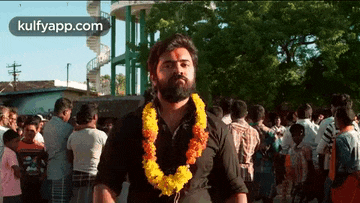 a man with a beard is wearing a garland around his neck .