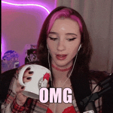 a woman with pink hair is holding a coffee mug with the word omg on it