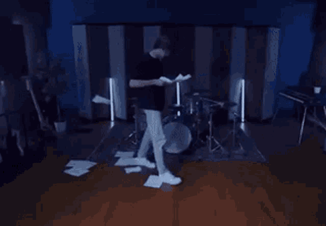 a man is standing in front of a drum set holding a piece of paper