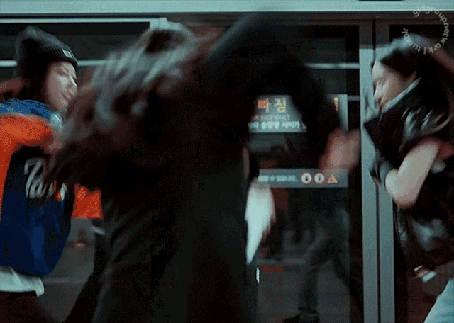 two women fighting in front of a sign that says ' warning ' on it