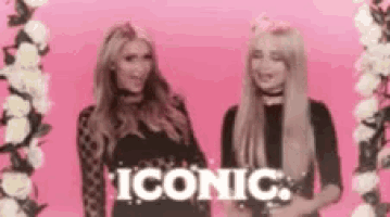 two women are standing next to each other in front of a pink background with the word iconic .