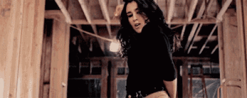 a woman is dancing in a room with a wooden ceiling .
