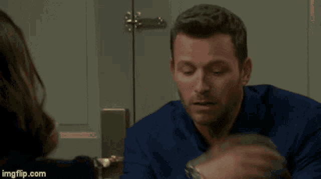 a man in a blue shirt is covering his face with his hand