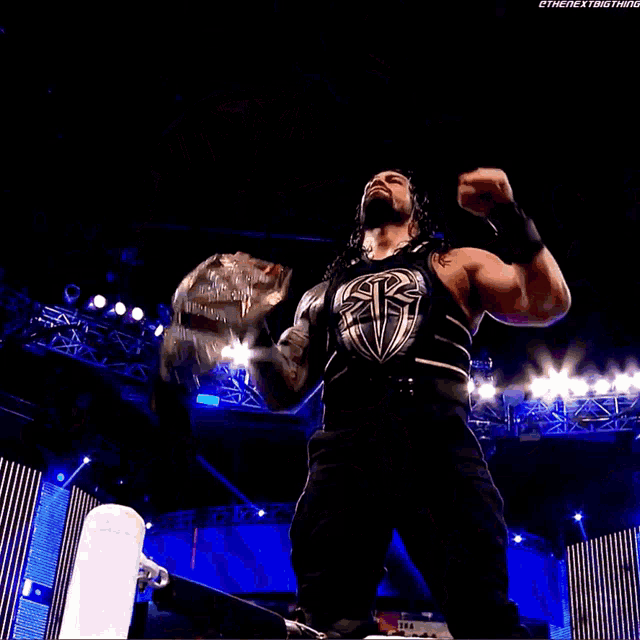 roman reigns is holding the wwe world heavyweight championship in the air