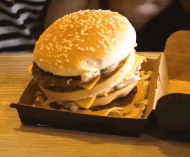 a hamburger with sesame seeds on it sits in a cardboard box