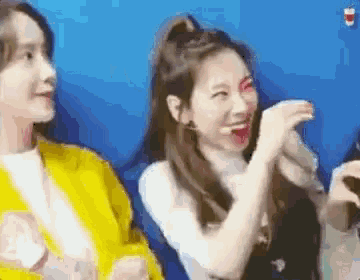 a group of women are sitting next to each other on a blue background .