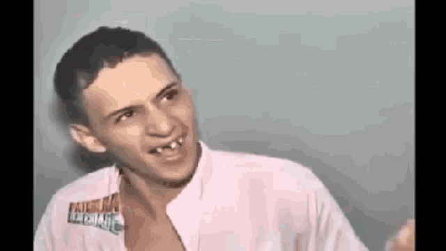 a young man with a missing tooth is smiling while wearing a white shirt .