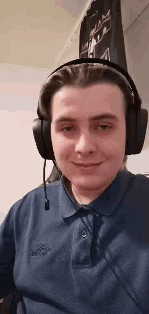 a man wearing headphones and a blue polo shirt is smiling .