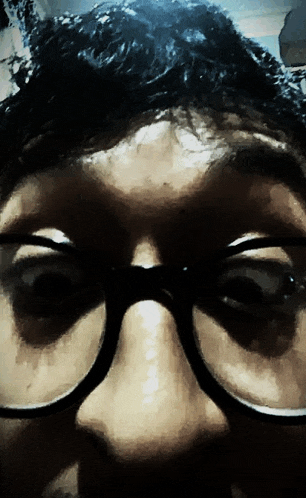 a close up of a person wearing glasses with a dark background