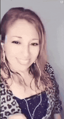 a woman wearing headphones and a leopard print top is smiling and looking at the camera .