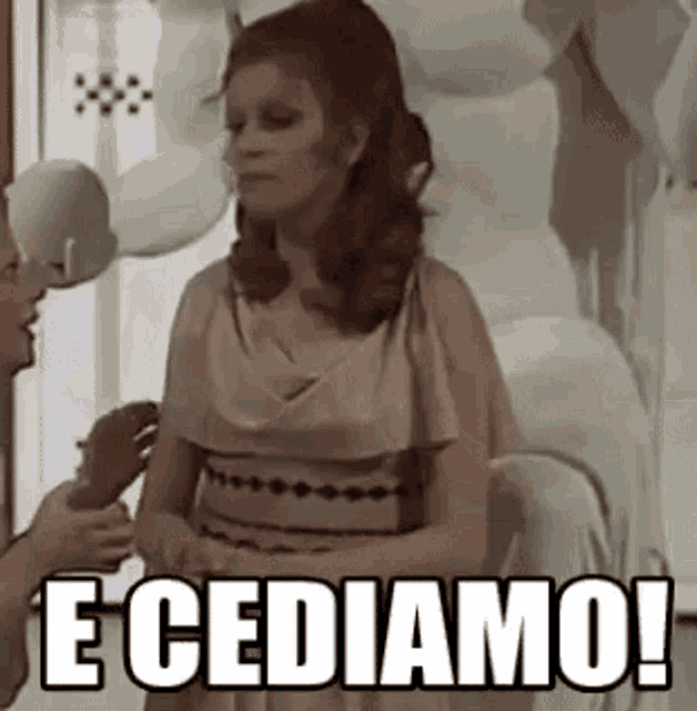 a woman in a dress is talking to a man in a room and the woman is saying e cediamo !