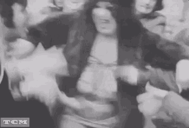 a black and white photo of a woman dancing in a crowd .