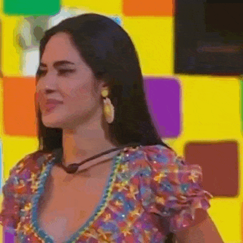 a woman wearing a colorful dress and earrings is standing in front of a yellow wall .