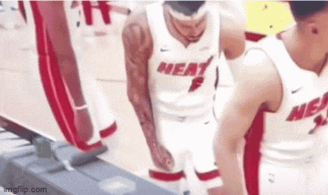 a group of basketball players are standing on a court . one of the players is wearing a heat jersey .