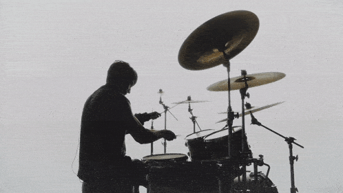 a silhouette of a man playing drums with a white background