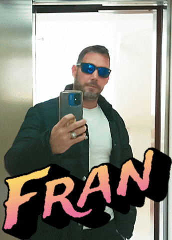 a man wearing sunglasses takes a selfie in front of a sign that reads fran