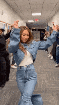 a woman is dancing in a hallway with her arms in the air .