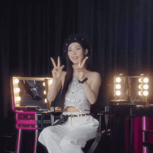 a woman in a crop top and white pants is giving the peace sign