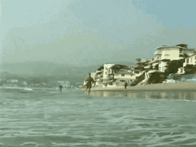 a man in red shorts is running into the ocean on a beach