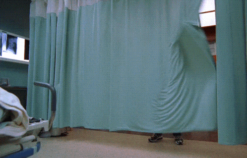 a man in a hospital room is holding a green curtain