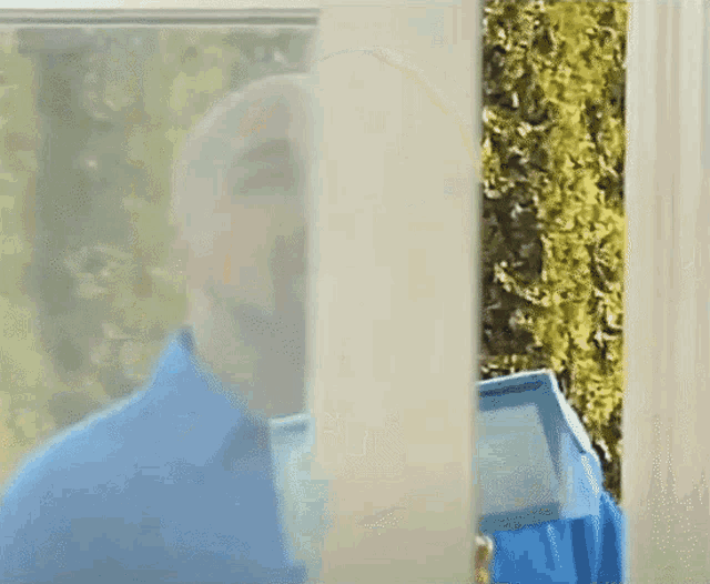 a man in a blue shirt is looking through a door