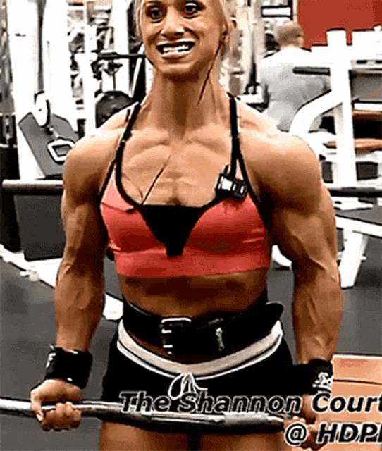 a woman is lifting a barbell in a gym with a sign that says the shannon court on it