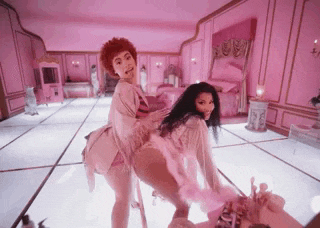 two women are dancing in a room with pink walls and a white floor .