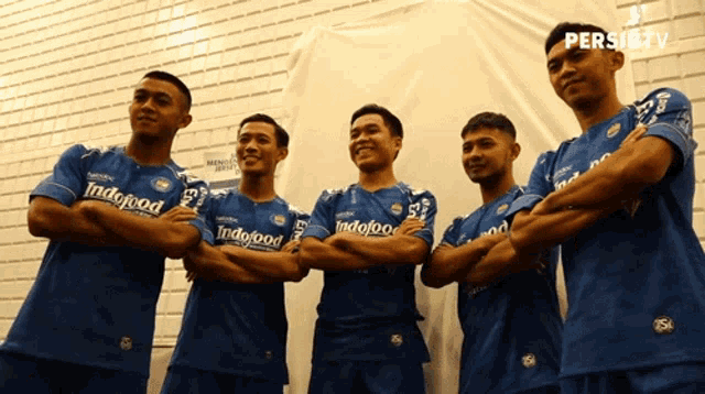 a group of soccer players wearing blue jerseys with indofood written on them