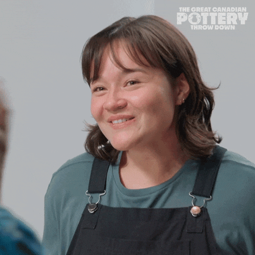 a woman in overalls is smiling in front of a sign that says the great canadian pottery throw down