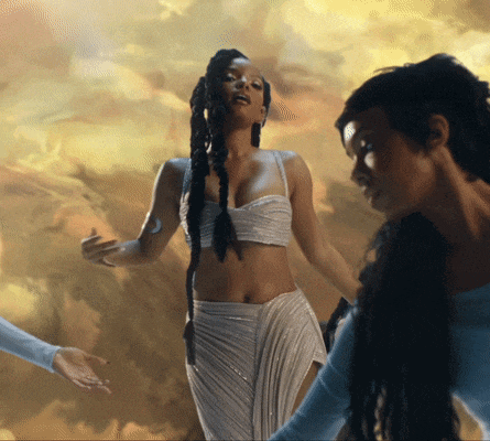 a woman in a white crop top and white skirt is standing next to another woman