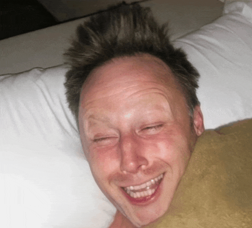 a man laying on a bed with his eyes closed and his mouth open