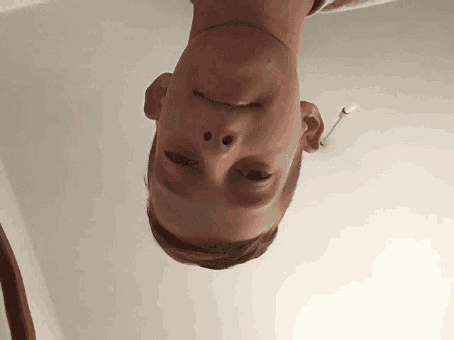 a young boy 's head is upside down and his eyes are closed