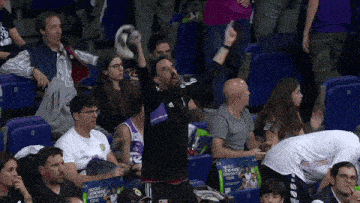 a group of people sitting in a stadium watching a basketball game with a sign that says ' la liga '