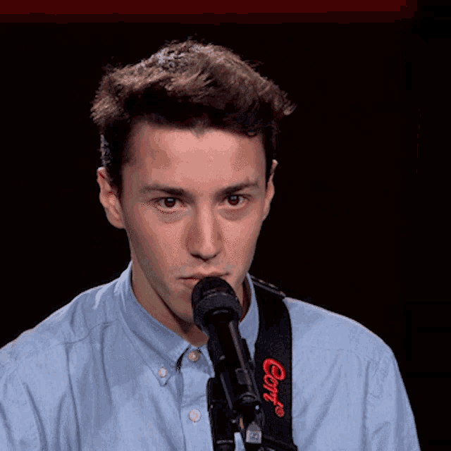 a young man singing into a microphone with a strap that says comf