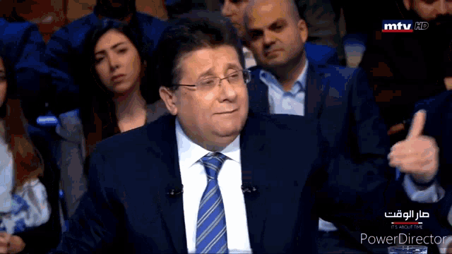 a man in a suit and tie is sitting in front of a group of people on a mtv hd channel