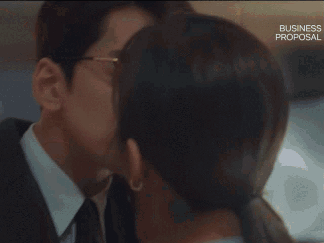 a man and a woman are kissing in a business proposal scene .