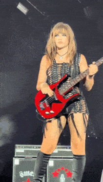 a woman playing a red guitar in front of an amplifier that says ame on it
