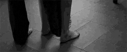 a black and white photo of a couple 's feet on a tile floor .