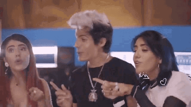 a man and two women are standing next to each other pointing at something .