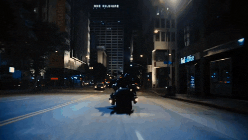 a person riding a motorcycle down a city street at night