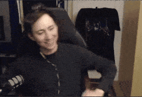 a man in a black sweater is sitting in a chair and smiling