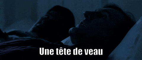 a man is sleeping in a dark room with the words une tete de veau below him