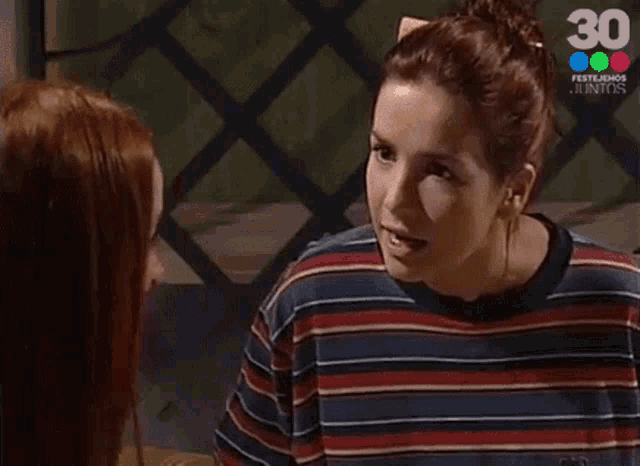 a woman in a striped shirt is talking to another woman in a striped shirt .