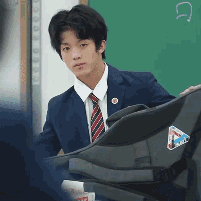 a young man in a suit and tie is holding a bag with a sticker on it that says ' triangle '